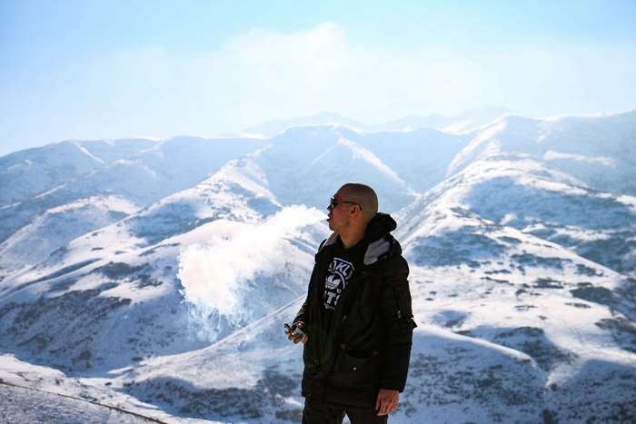 Man vaping in snow-capped mountains