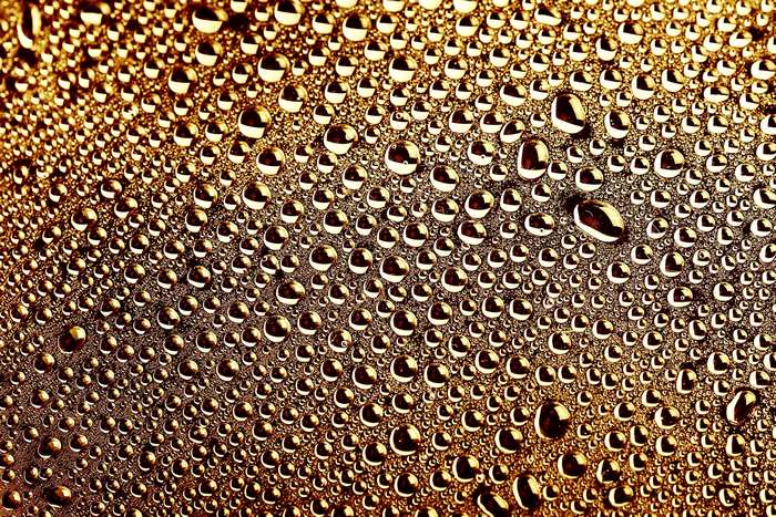 Close-up of golden water droplets on a textured surface