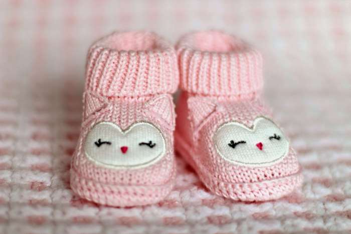 Pink knitted baby booties with owl faces