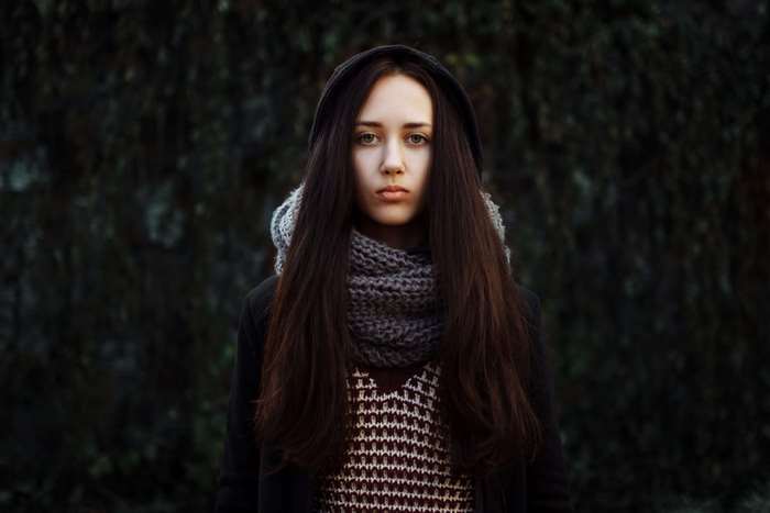 Young woman with long brown hair wearing a hooded jacket and scarf