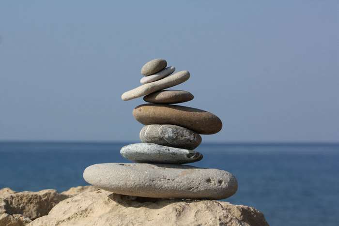 Stack of balanced stones on a beach with the ocean in the background