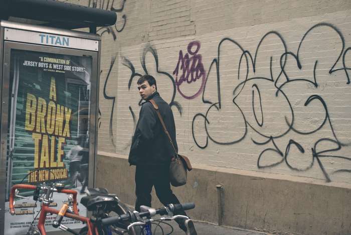 Man walking past A Bronx Tale musical poster in NYC