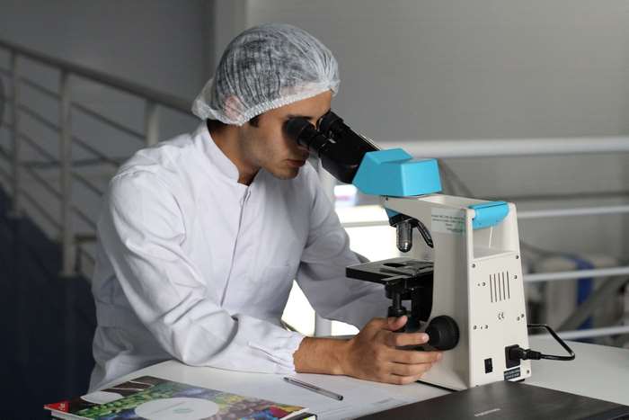 Man in lab coat using a microscope in a laboratory