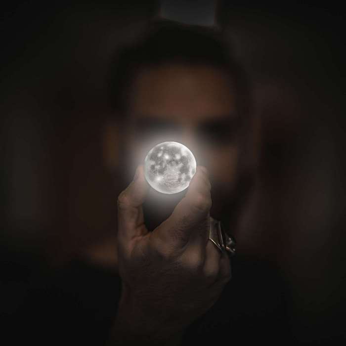 Man holding a small glowing moon in his hand
