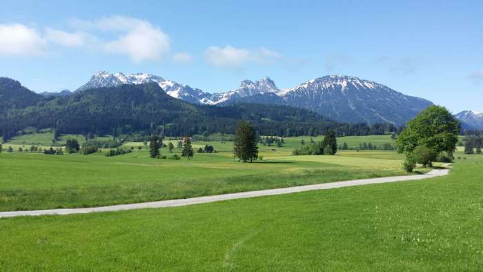 Green hills and snow-capped mountains under a blue sky