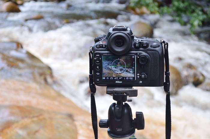 Nikon DSLR camera on tripod by a river