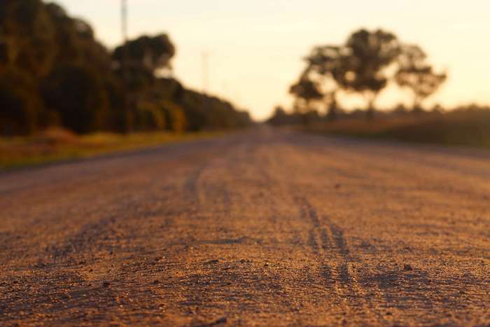 Dirt road with trees at sunset
