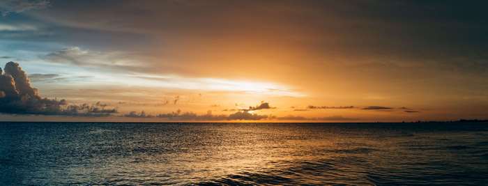 Panoramic ocean sunset with dramatic clouds