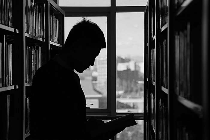 Silhouette of a man reading a book in a library