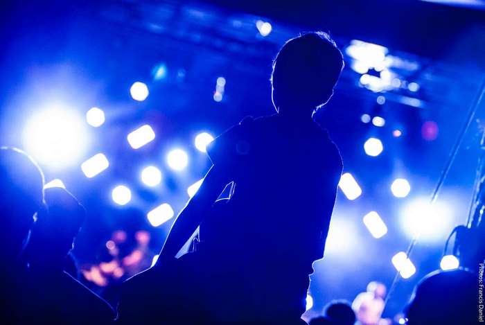 Silhouette of a person at a concert with blue stage lights