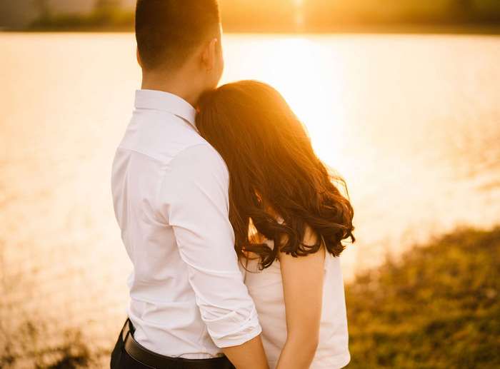Couple embracing by a lake at sunrise