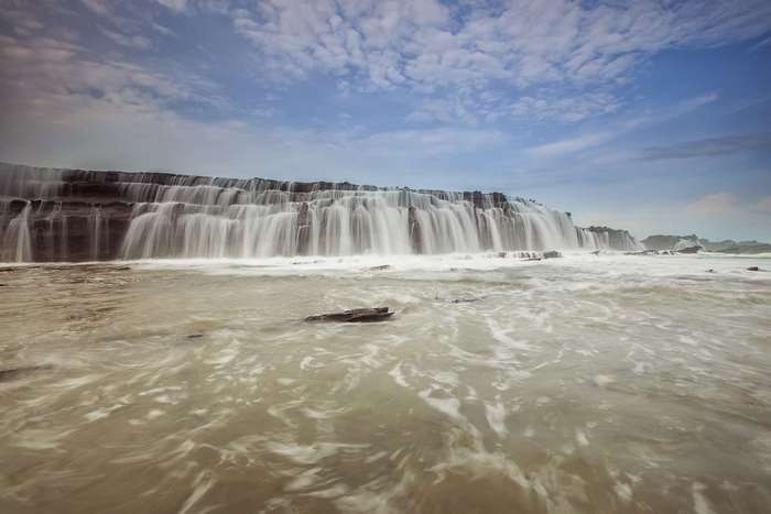 Waterfall cascading over rocks into the ocean