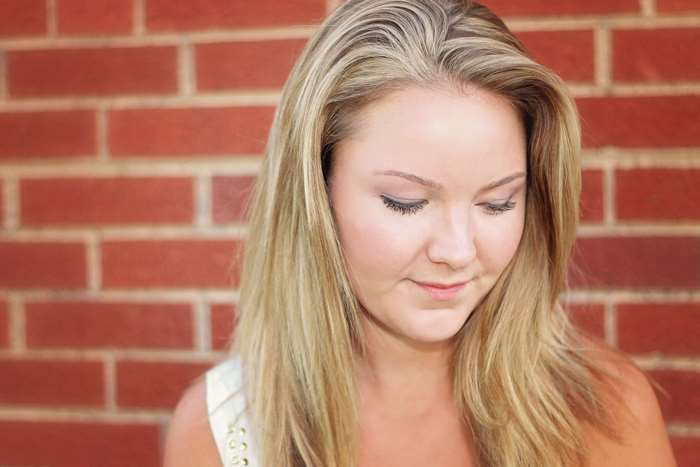 Blonde Woman Smiling Against Brick Wall