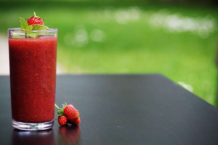 Strawberry smoothie in a glass with strawberries and mint