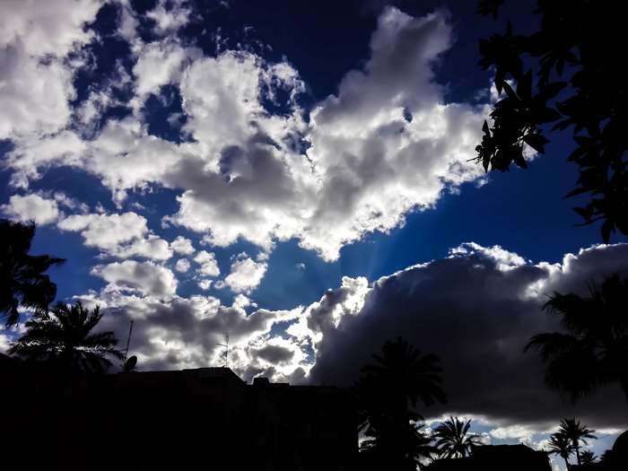 Dramatic clouds over silhouetted buildings and palm trees in Morocco