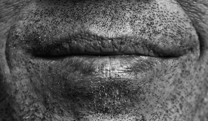 Close-up of a man's mouth with beard stubble