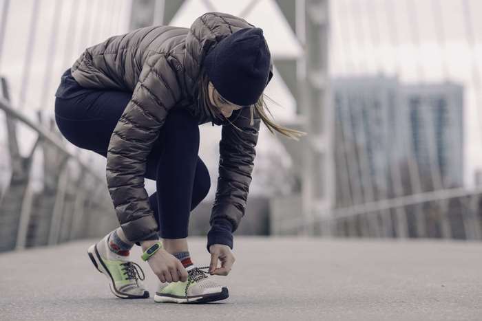 Woman tying shoelaces on a bridge in the city