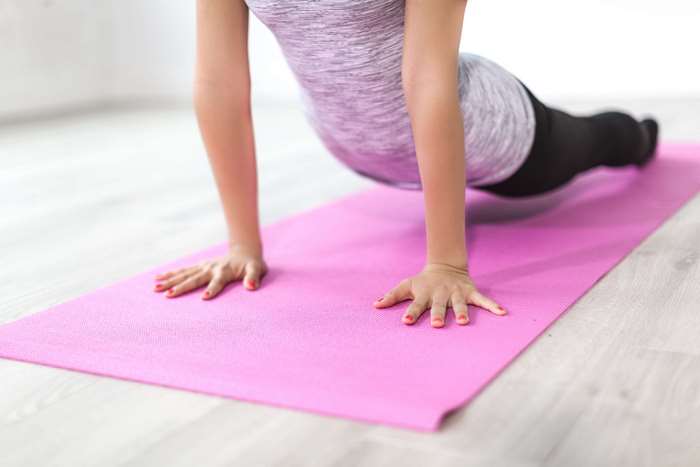 Woman doing yoga on a pink mat