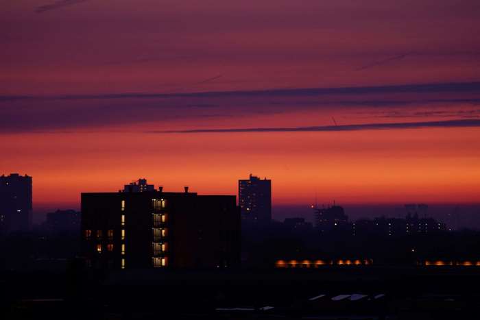 Cityscape at dusk with colorful sky and silhouetted buildings