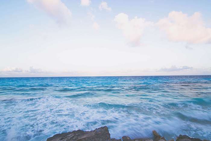 Ocean waves crashing on rocks under a blue sky