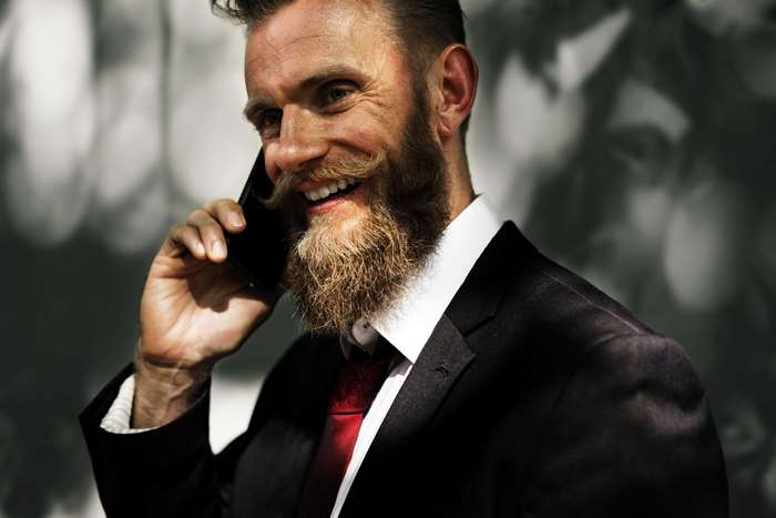 Man with beard talking on smartphone in suit 4K