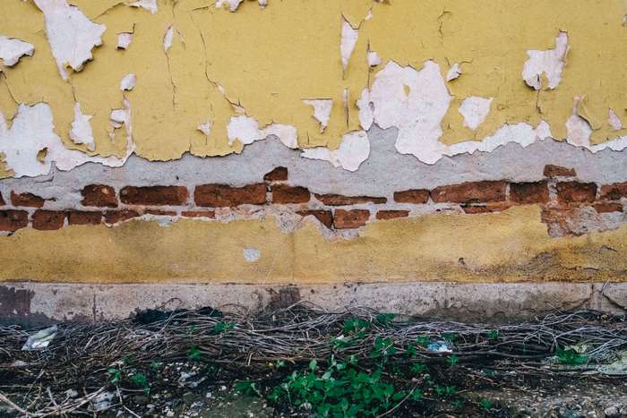 Peeling yellow paint on a brick wall texture 4K