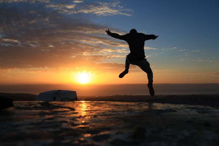 Man jumping at sunset over water