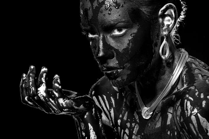 Woman covered in black paint with jewelry