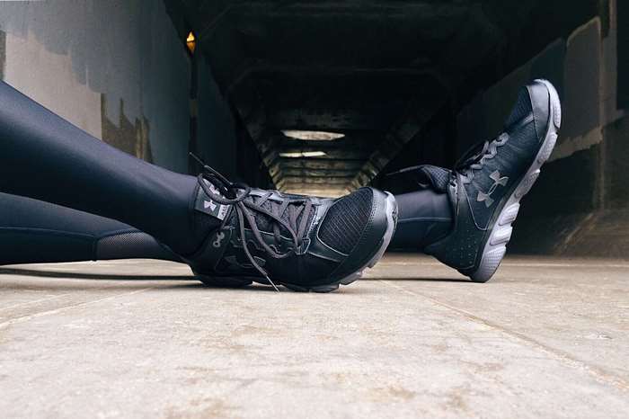 Person wearing Under Armour sneakers in a tunnel