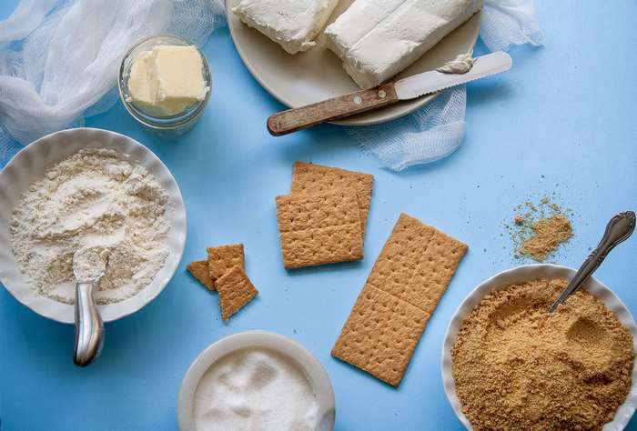 Ingredients for a dessert: cream cheese, butter, flour, sugar, graham crackers