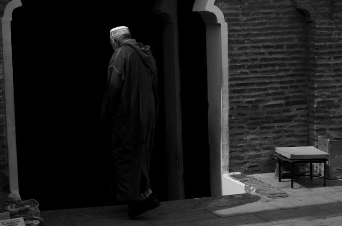 Man in traditional clothing entering a dark doorway in Marrakech