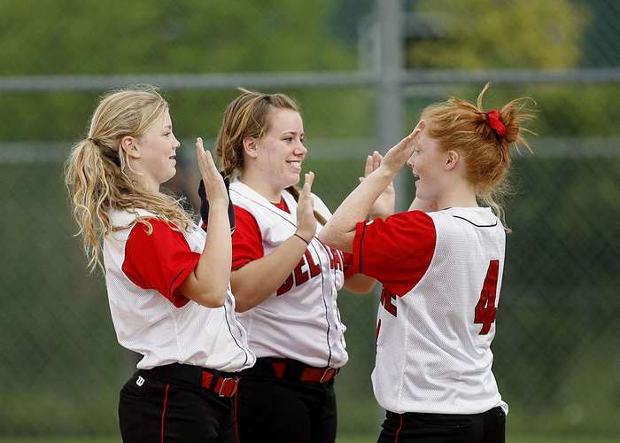 Three young female softball players celebrating