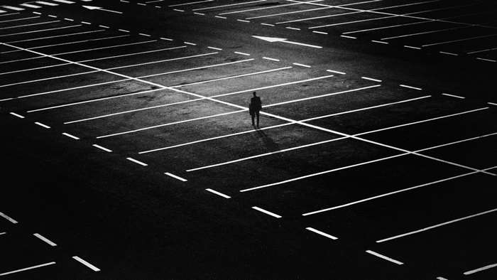 Man walking alone in a dark parking lot at night