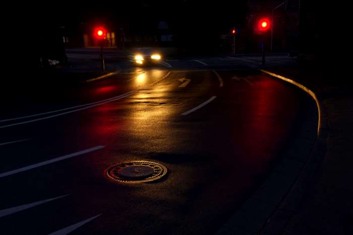 Night intersection with red traffic lights and car headlights