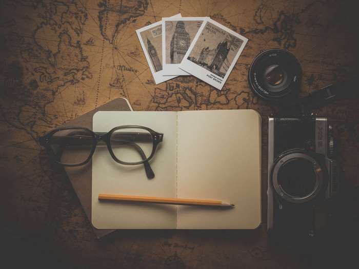 Travel essentials: camera, glasses, notebook, map, and photos