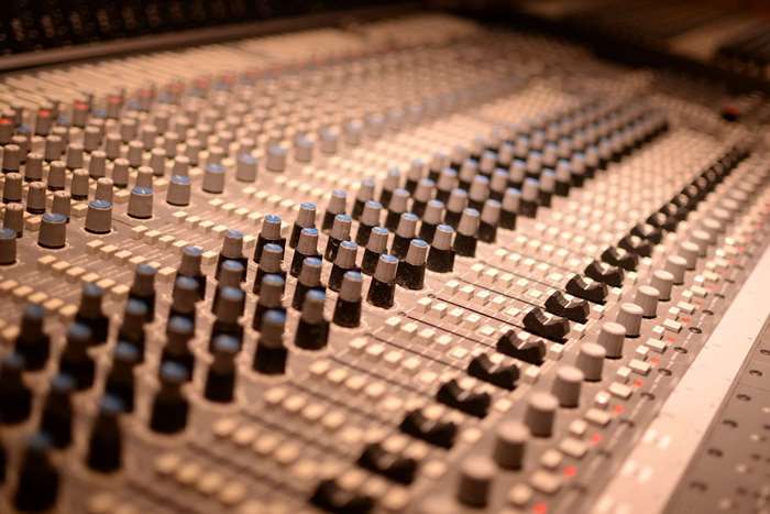 Close up of a mixing console with faders and knobs