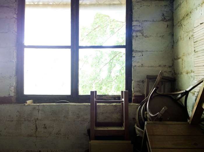 Abandoned room with window and stacked furniture