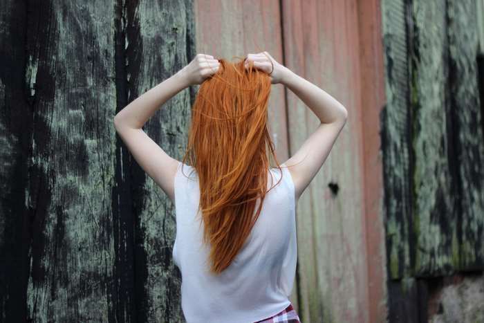 Woman with red hair in front of wooden wall