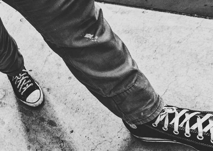 Person wearing Converse sneakers and jeans walking on concrete