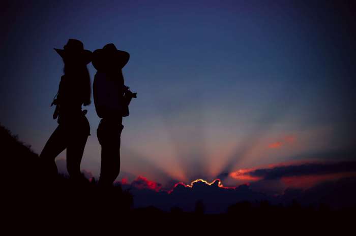 Two girls in cowboy hats at sunset