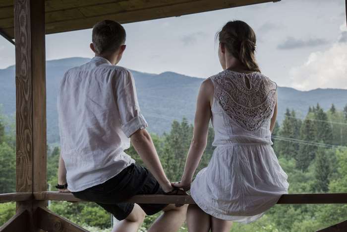 Couple holding hands on a balcony overlooking mountains