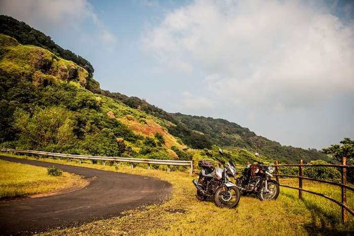 Two motorcycles parked on a roadside with a mountain landscape