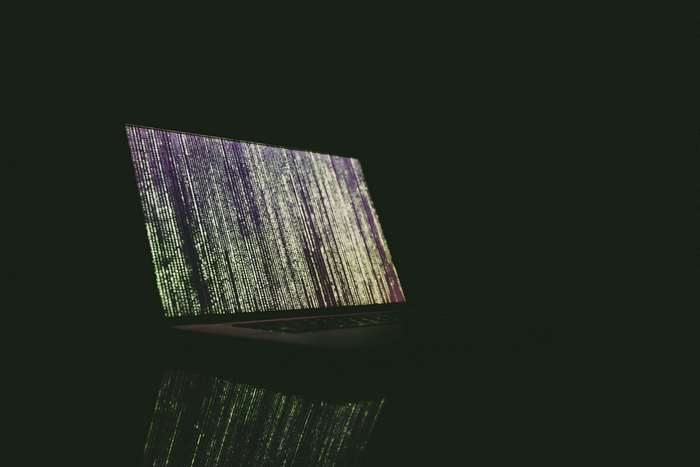 Laptop displaying matrix code in dark room 4K