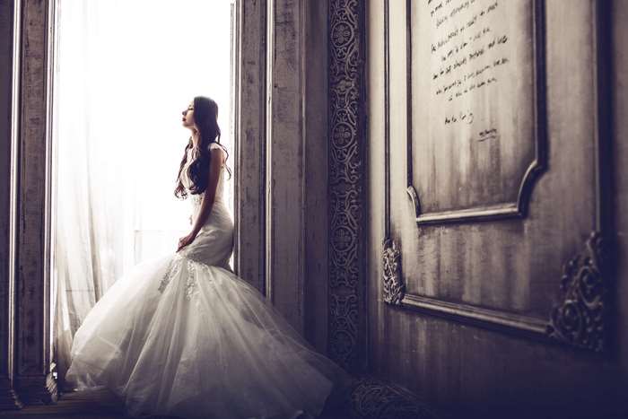 Woman in wedding dress by window