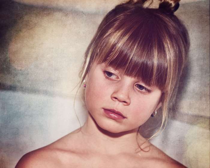 Young girl with blonde hair in a bun, looking down