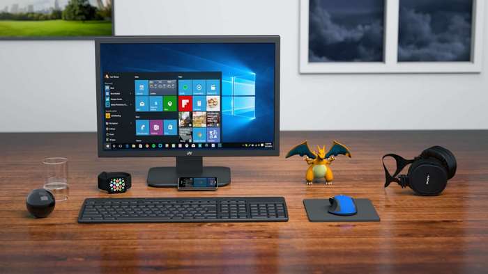 Computer monitor, keyboard, mouse, headphones, and figurines on a desk