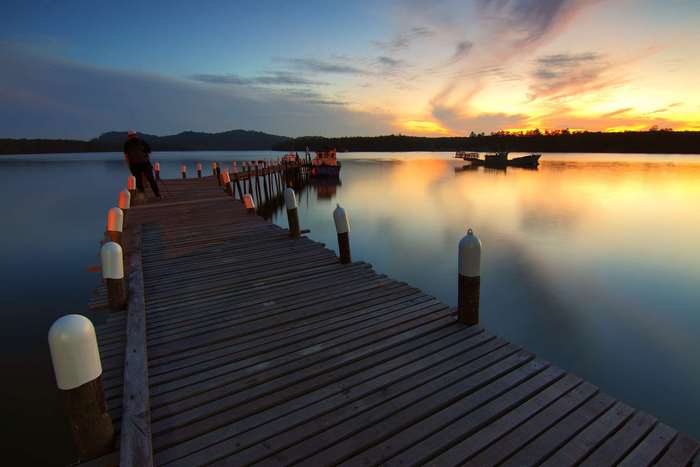 Wooden pier at sunset with boats on the water