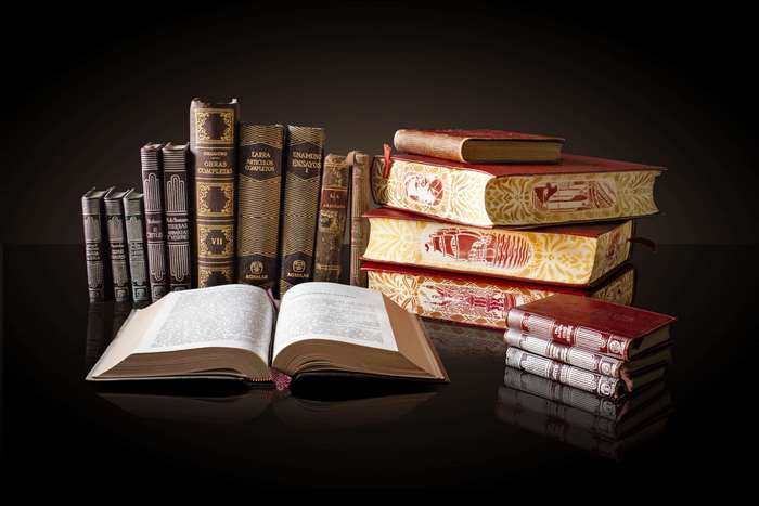 Collection of antique books on a reflective surface