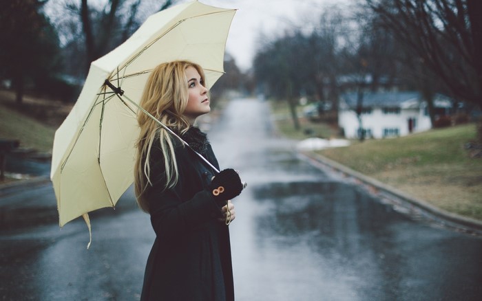 Blonde girl with umbrella on a rainy street