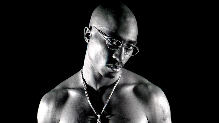 Tupac Shakur wearing glasses and necklace